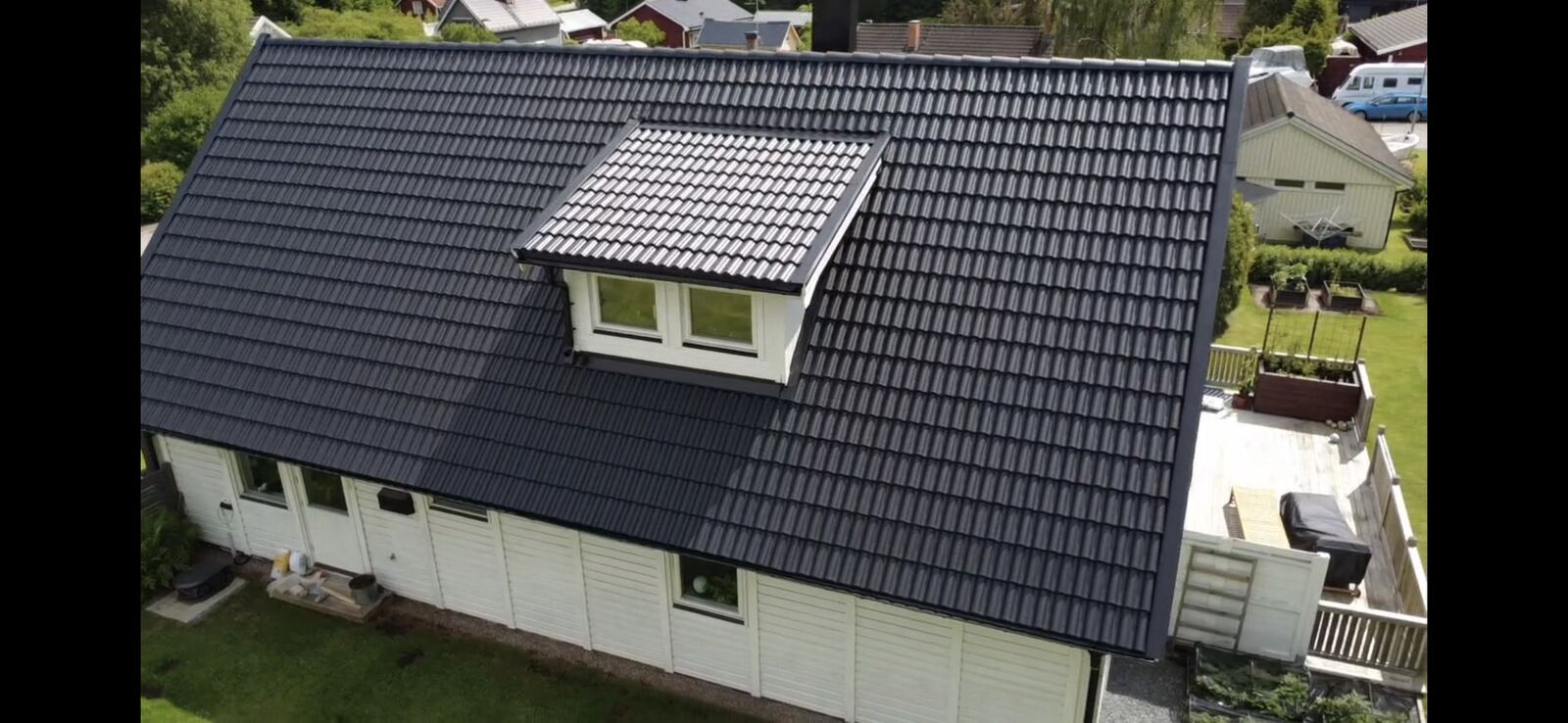 Drönarfoto, nytäckt svart tegeltak på vitt hus