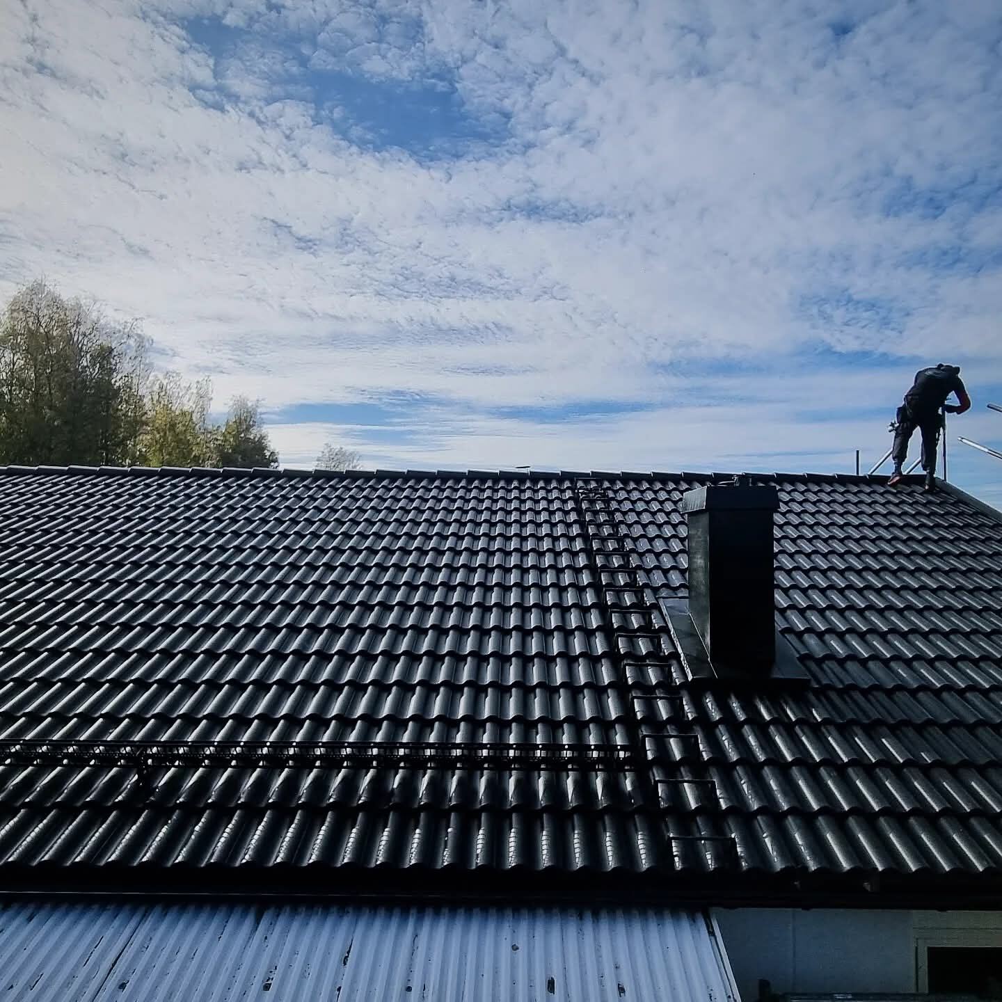 Takläggare siluett mot himmel på svart tegeltak