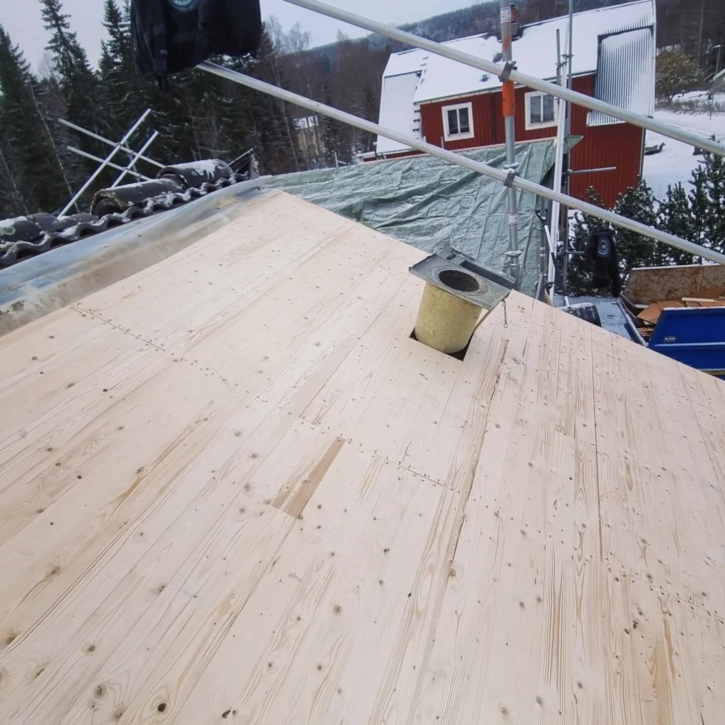 Ny träpanel på tak, vintertid med snö i bakgrunden